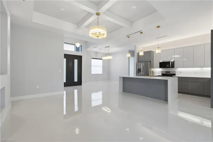 Kitchen featuring a center island with sink, beam ceiling, hanging light fixtures, modern cabinets, and coffered ceiling