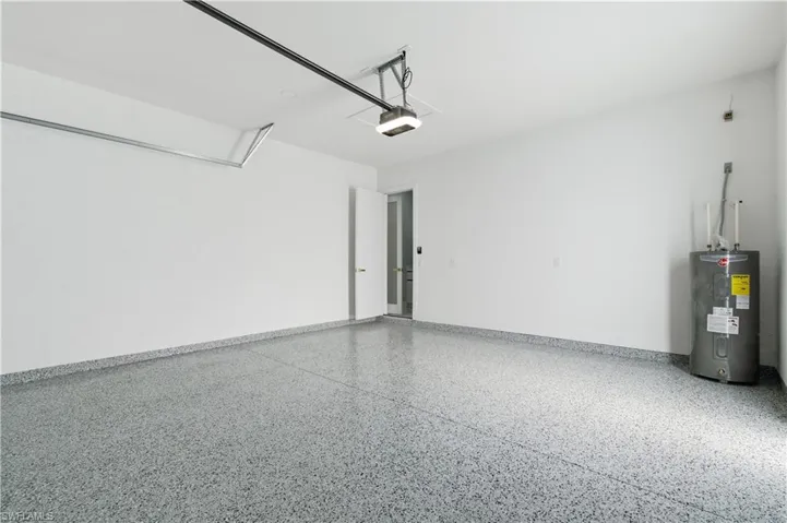 Garage featuring electric water heater and baseboards