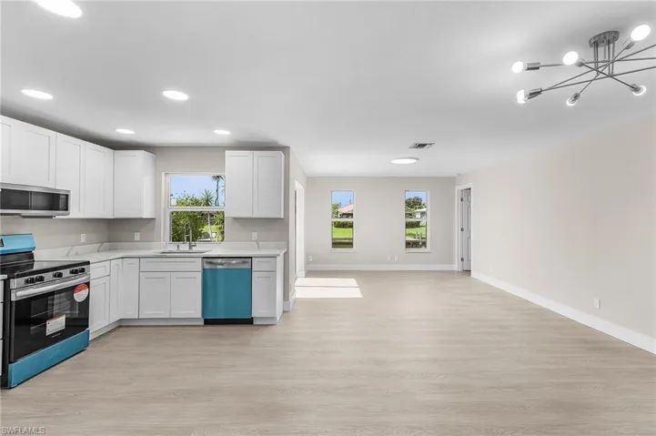 Kitchen with stainless steel appliances, light wood-style flooring, white cabinetry, recessed lighting, and a chandelier