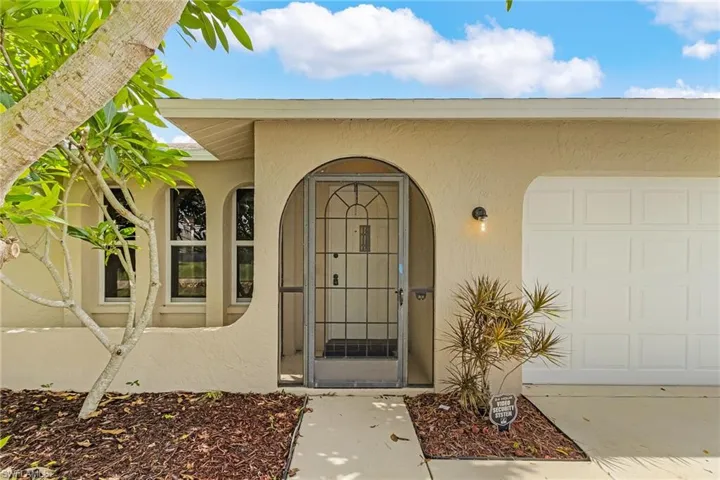 View of exterior entry with an attached garage and stucco siding