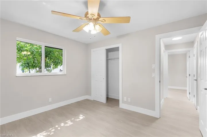 Unfurnished bedroom with light wood-type flooring, a closet, and a ceiling fan