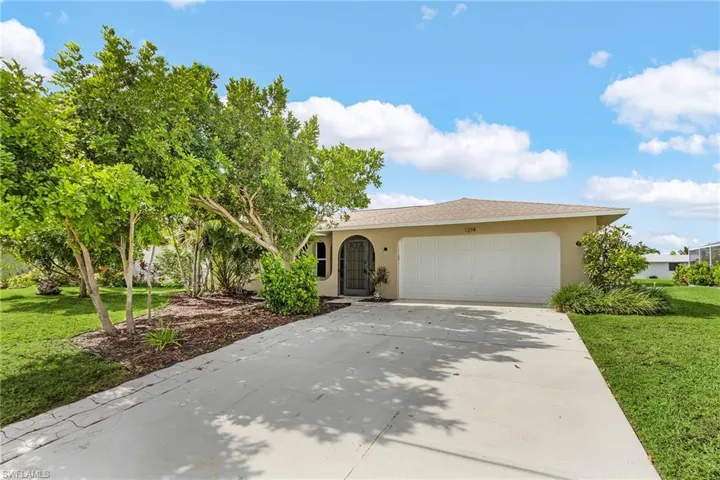 View of front of house featuring a front yard, stucco siding, an attached garage, and concrete driveway