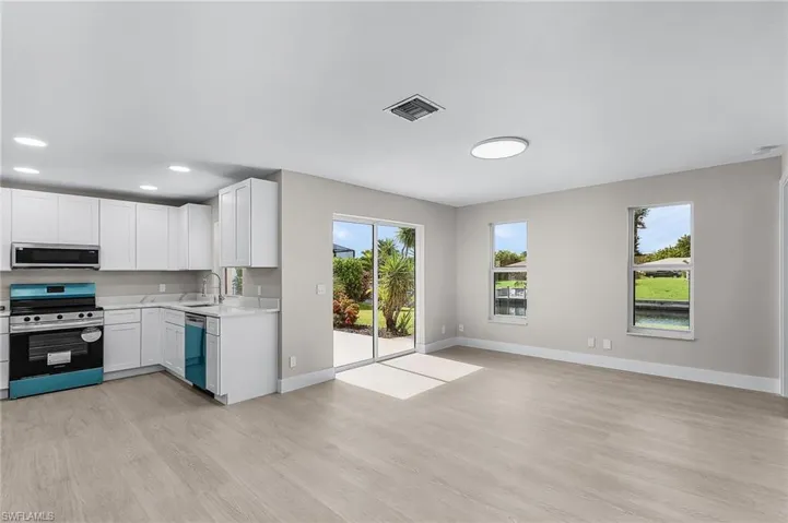 Kitchen with stainless steel appliances, white cabinets, light wood-style flooring, recessed lighting, and open floor plan