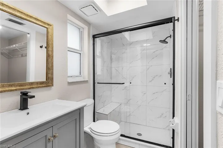 Bathroom featuring a marble finish shower and vanity