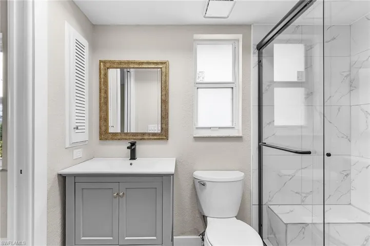 Full bathroom with vanity, a marble finish shower, and a textured wall