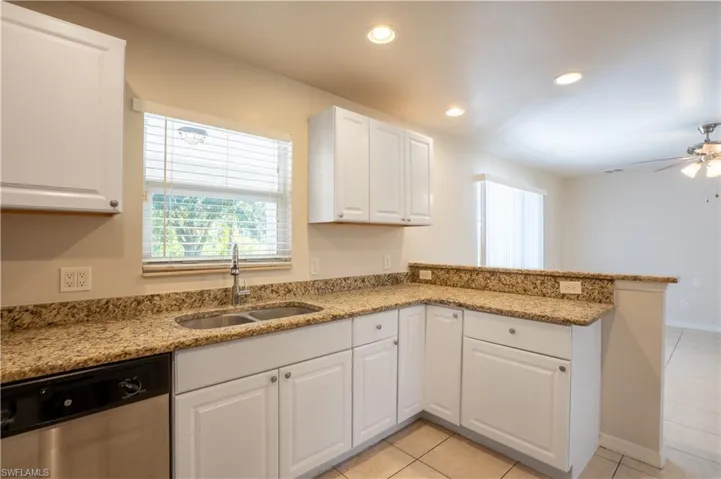Kitchen featuring light stone counters, dishwasher, white cabinets, a peninsula, and recessed lighting