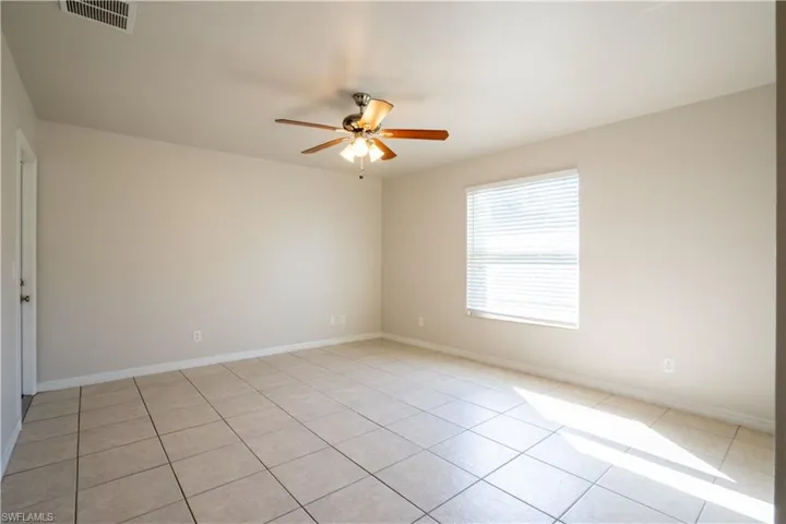 Empty room with light tile patterned floors and a ceiling fan