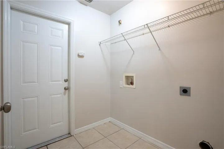Washroom with hookup for an electric dryer, light tile patterned flooring, and washer hookup