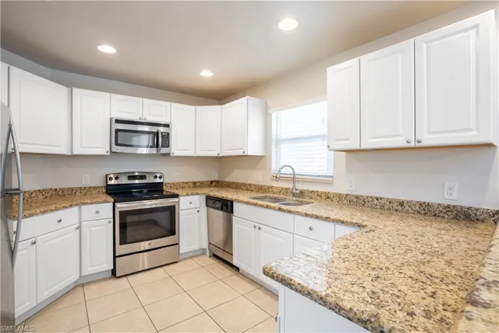 Kitchen featuring stainless steel appliances, white cabinets, light stone counters, recessed lighting, and light tile patterned floors