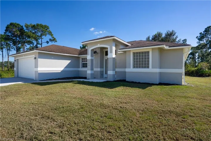 Ranch-style house with stucco siding, a front yard, driveway, an attached garage, and a shingled roof