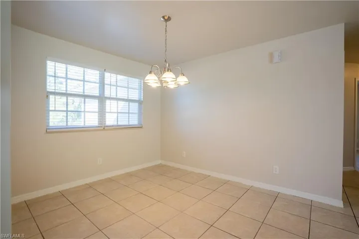 Spare room with a chandelier and light tile patterned flooring