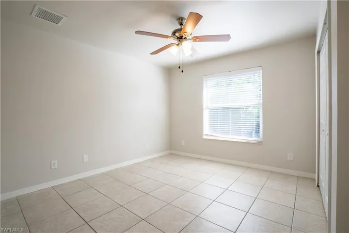 Empty room with light tile patterned floors and a ceiling fan