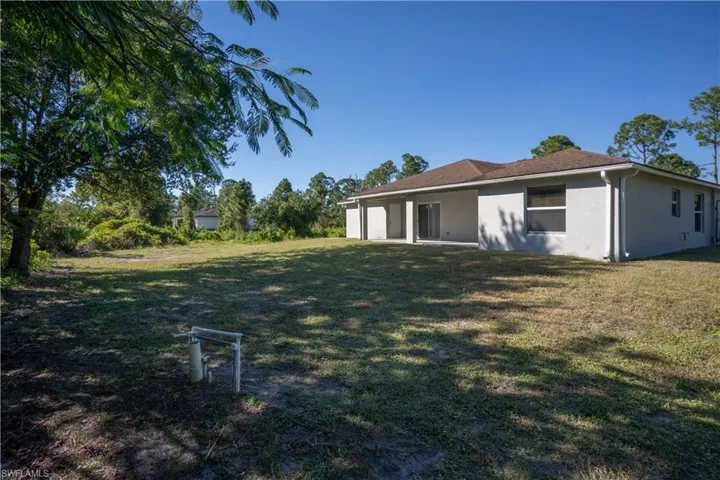 Back of house featuring a patio, a lawn, and stucco siding