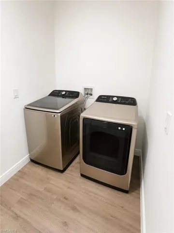 Dedicated laundry area featuring wood-finish flooring, white baseboards, and bright white walls