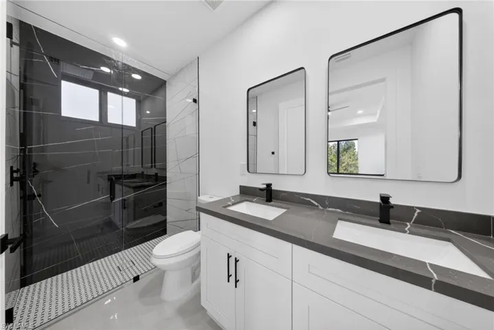 Contemporary bathroom featuring a spacious glass-enclosed shower with black-veined wall tiles and a mosaic tile floor