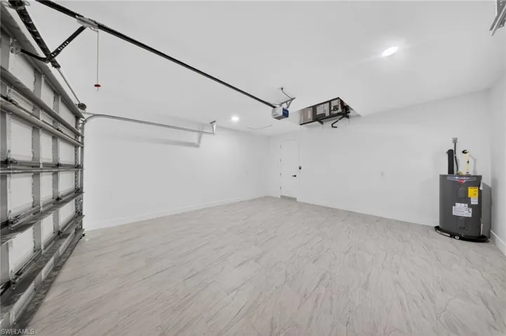 Spacious garage featuring light-toned, wood-finish flooring and a white overhead garage door