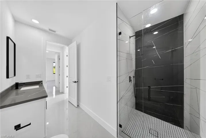 Sleek bathroom featuring a spacious glass-enclosed shower with black and white patterned tile walls
