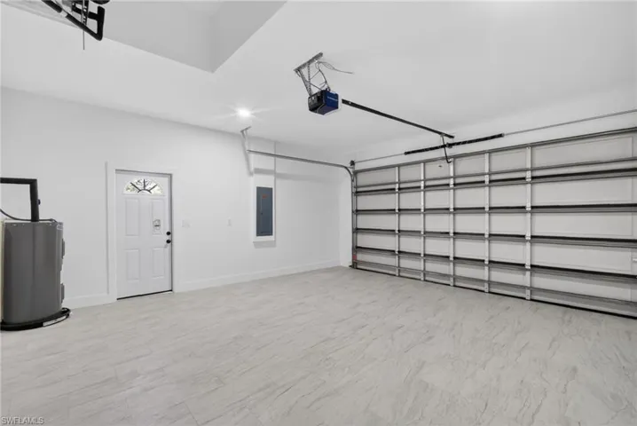 Spacious garage featuring light-toned tile flooring and a sectional overhead door with an automatic opener