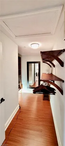 Hallway with crown molding, baseboards, and wood finished floors