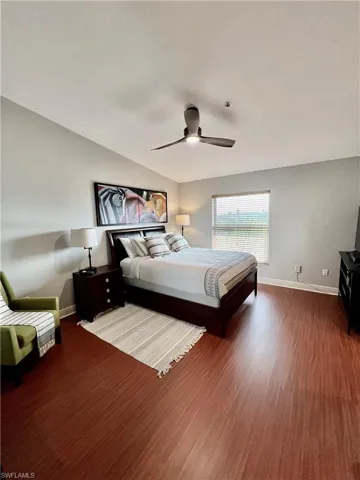 Bedroom featuring a ceiling fan, lofted ceiling, baseboards, and wood finished floors