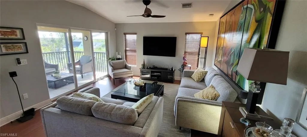 Living room with visible vents, baseboards, lofted ceiling, and ceiling fan