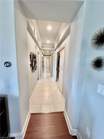 Hallway with baseboards, light wood-style floors, and crown molding