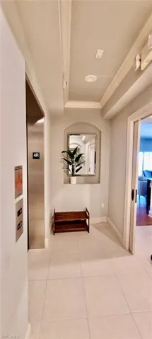 Hallway featuring tile patterned flooring, elevator, baseboards, and ornamental molding