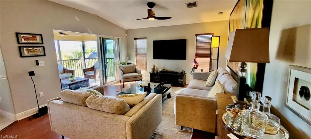 Living area with visible vents, wood finished floors, baseboards, ceiling fan, and vaulted ceiling