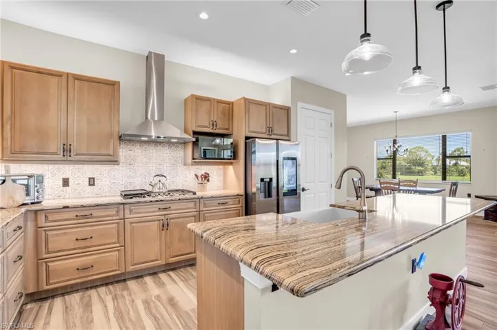 Kitchen with a center island with sink, stainless steel appliances, sink, and a tray ceiling
