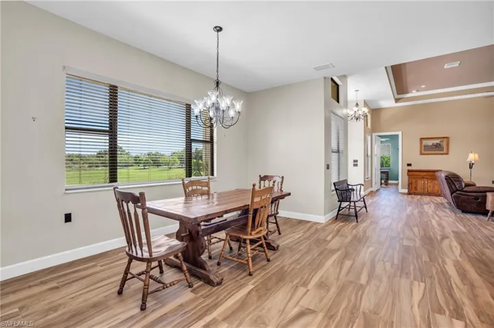 Kitchen with a tray ceiling, hanging light fixtures, dishwasher, a center island with sink, and light hardwood / wood-style flooring