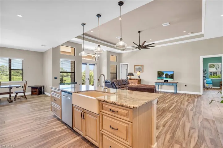 Kitchen featuring appliances with stainless steel finishes, a center island with sink, wall chimney range hood, sink, and light hardwood / wood-style floors