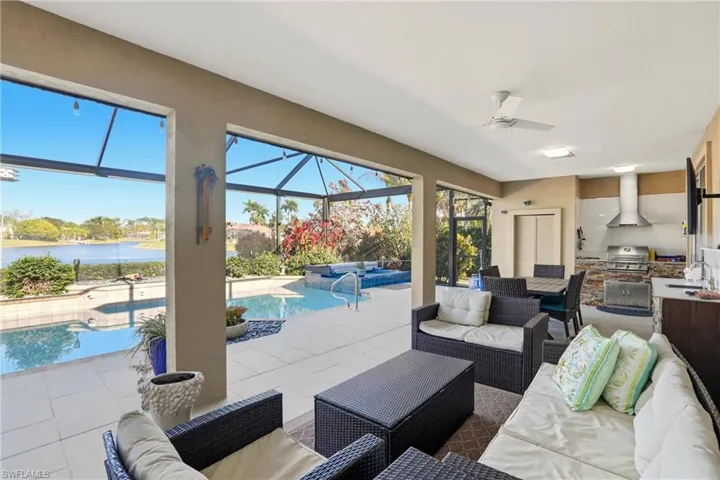 Living room with a sunroom, a water view, tile patterned flooring, and a ceiling fan