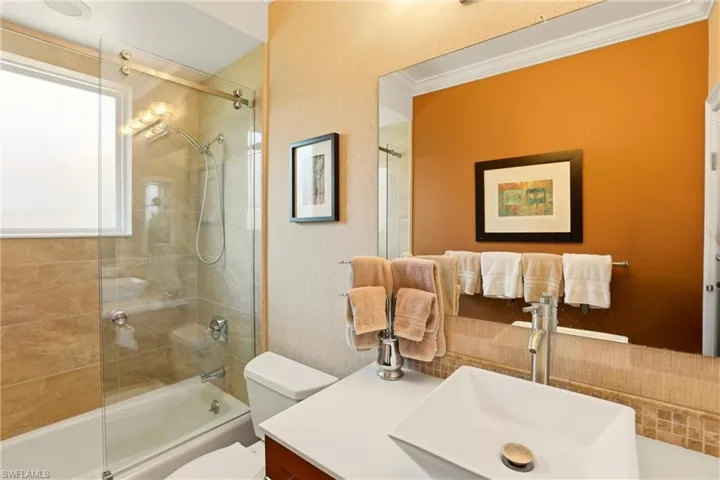 Bathroom featuring vanity, enclosed tub / shower combo, and ornamental molding