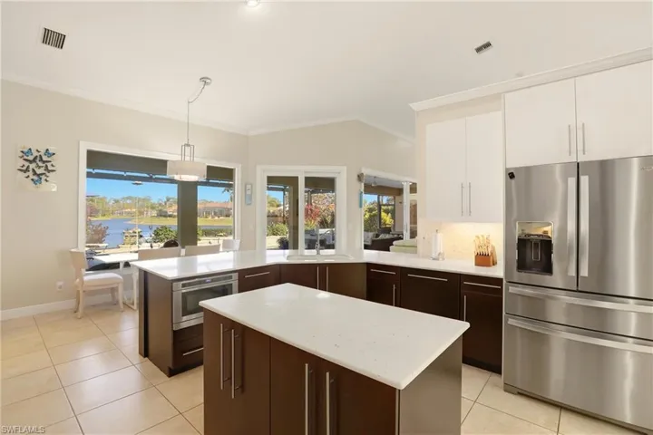 Two tone kitchen with stainless steel appliances, a peninsula, decorative backsplash, decorative light fixtures, and a center island