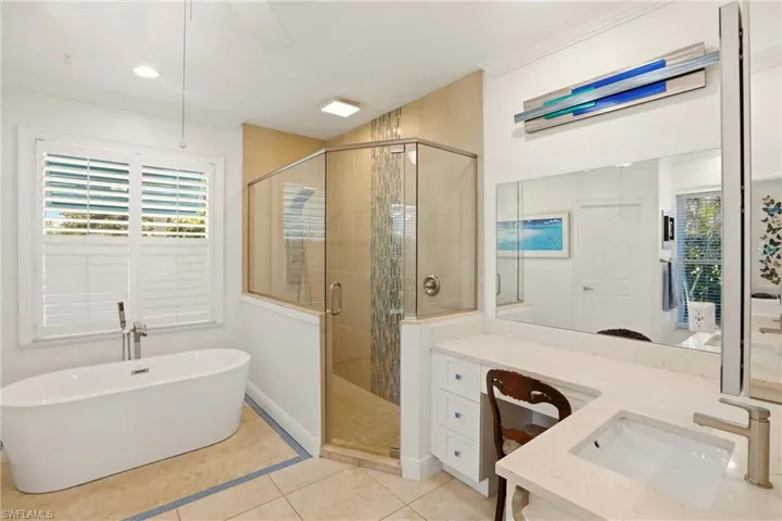 Bathroom featuring a stall shower, vanity, light tile patterned flooring, and a freestanding bath