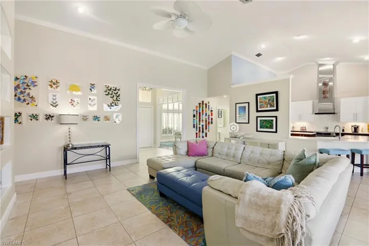 Living area featuring ceiling fan, ornamental molding, light tile patterned floors, and lofted ceiling
