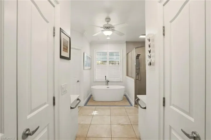 Bathroom with a shower stall, light tile patterned floors, a freestanding bath, ceiling fan, and ornamental molding