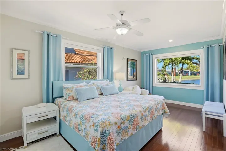 Bedroom featuring hardwood / wood-style floors, multiple windows, ceiling fan, a water view, and ornamental molding