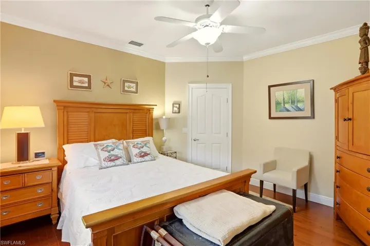 Bedroom with crown molding, dark wood-style flooring, and a ceiling fan