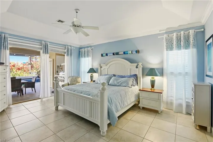 Bedroom featuring multiple windows, ceiling fan, a raised ceiling, and light tile patterned flooring