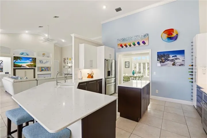 Kitchen with a center island, a peninsula, a ceiling fan, light tile patterned floors, and ornamental molding