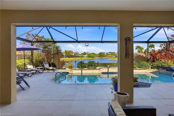 Swimming pool featuring a sunroom, a water view, a patio, and a lanai