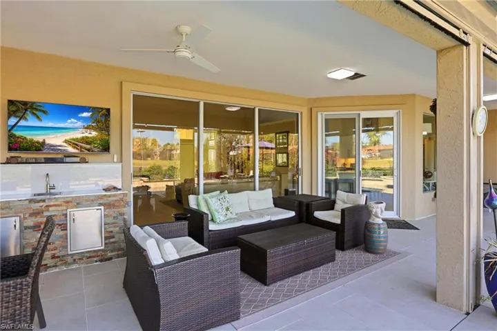 View of patio featuring a ceiling fan and an outdoor kitchen with living area