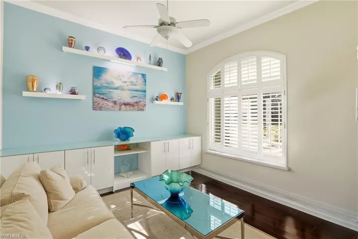 Sitting room featuring dark wood finished floors, crown molding, and ceiling fan