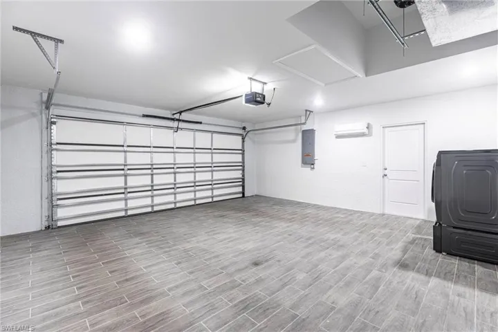 Garage featuring washer / dryer, electric panel, and a garage door opener