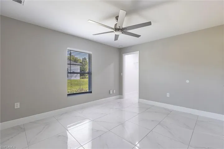 Spare room with light marble finish flooring and a ceiling fan