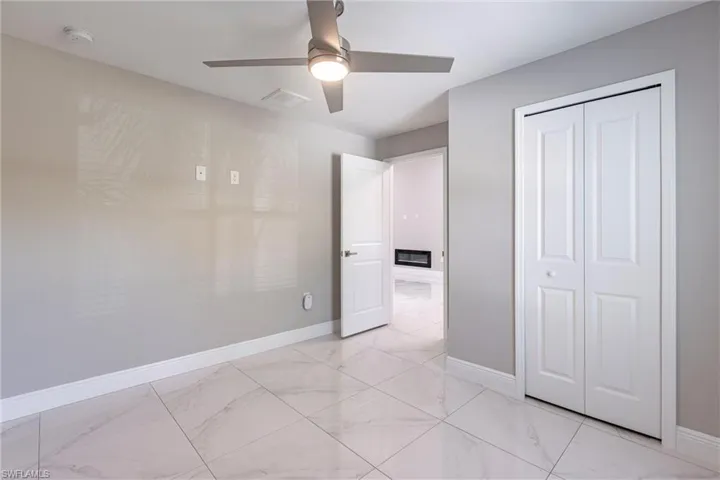 Unfurnished bedroom featuring light marble finish flooring, a closet, and a ceiling fan