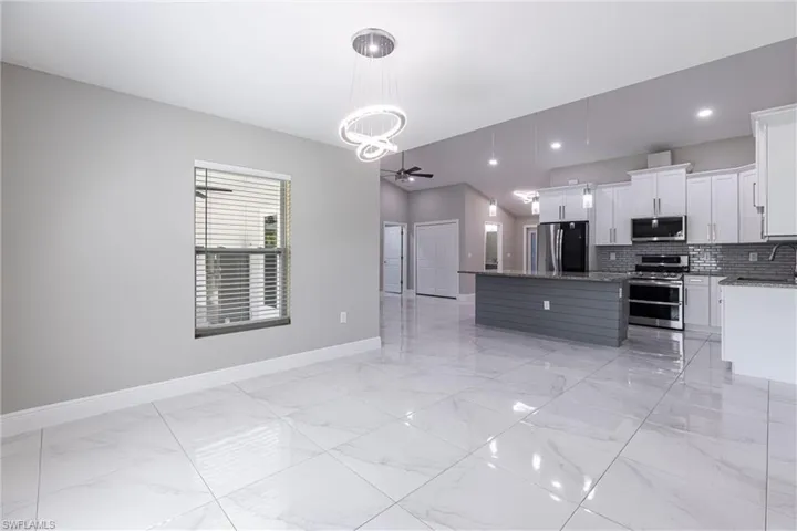 Kitchen featuring stainless steel appliances, light marble finish flooring, backsplash, a center island, and recessed lighting
