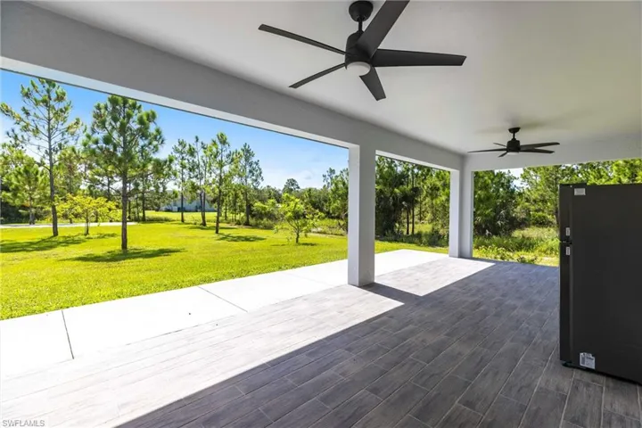 View of patio / terrace with a ceiling fan, a water view, and view of wooded area