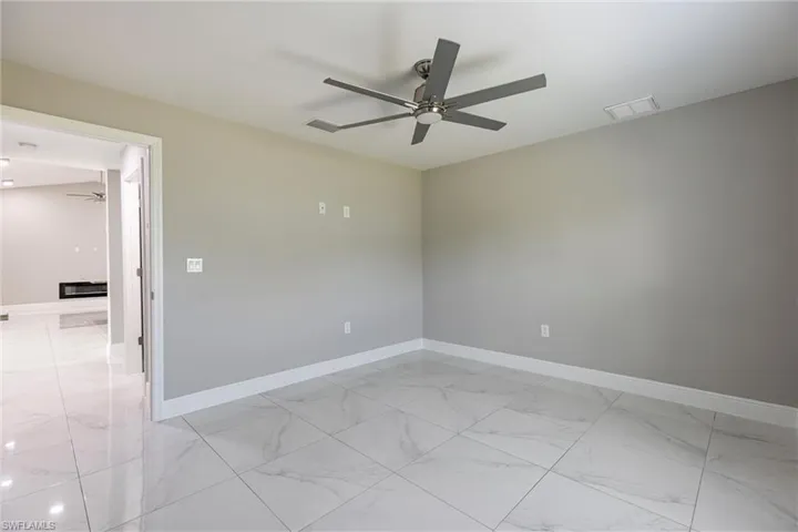 Empty room with a ceiling fan and light marble finish flooring